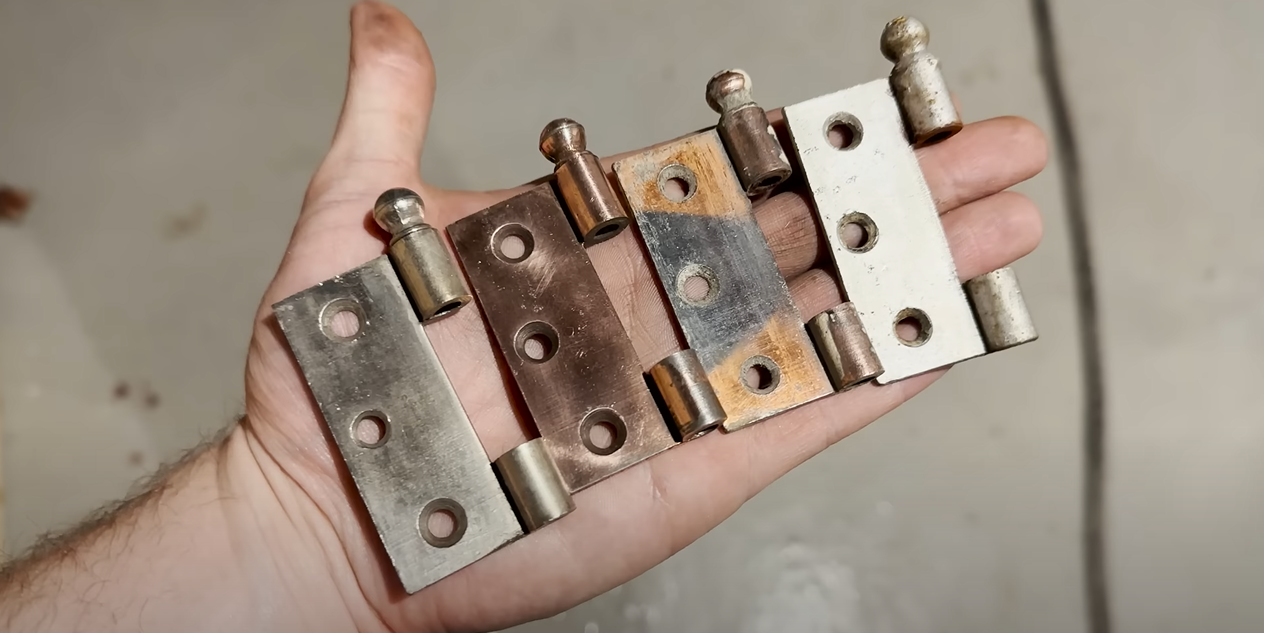 A hand holding various door hinges on its palm