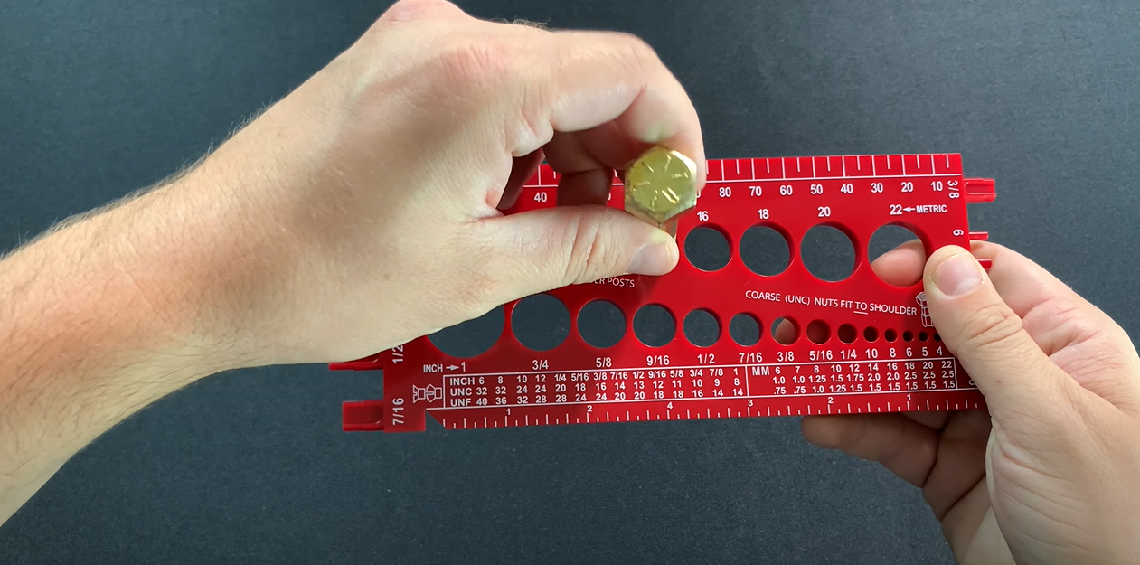 Hand measuring a nail with a chart