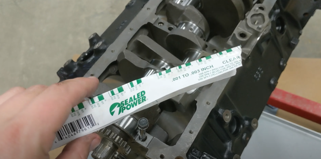 Hand holding plastic gauge with a machine beneath