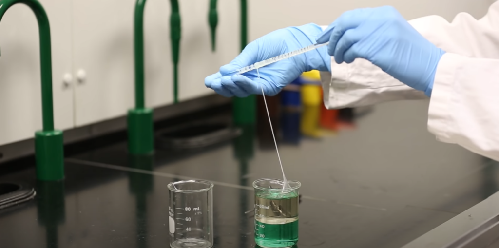 Hand making nylon inside a laboratory with beakers on the table