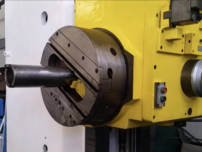 A close-up of a yellow and white industrial boring machine with a large chuck and a protruding cylindrical component